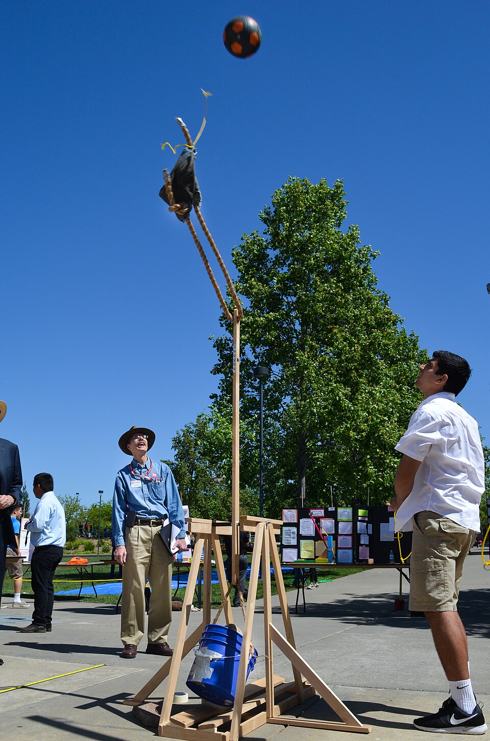 A student-built wooden trebuchet launching a ball at an outdoor school event